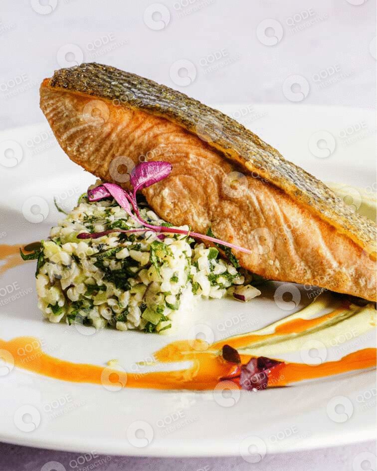 Pan-seared fish fillet served with herb risotto and garnishes on a white plate.
