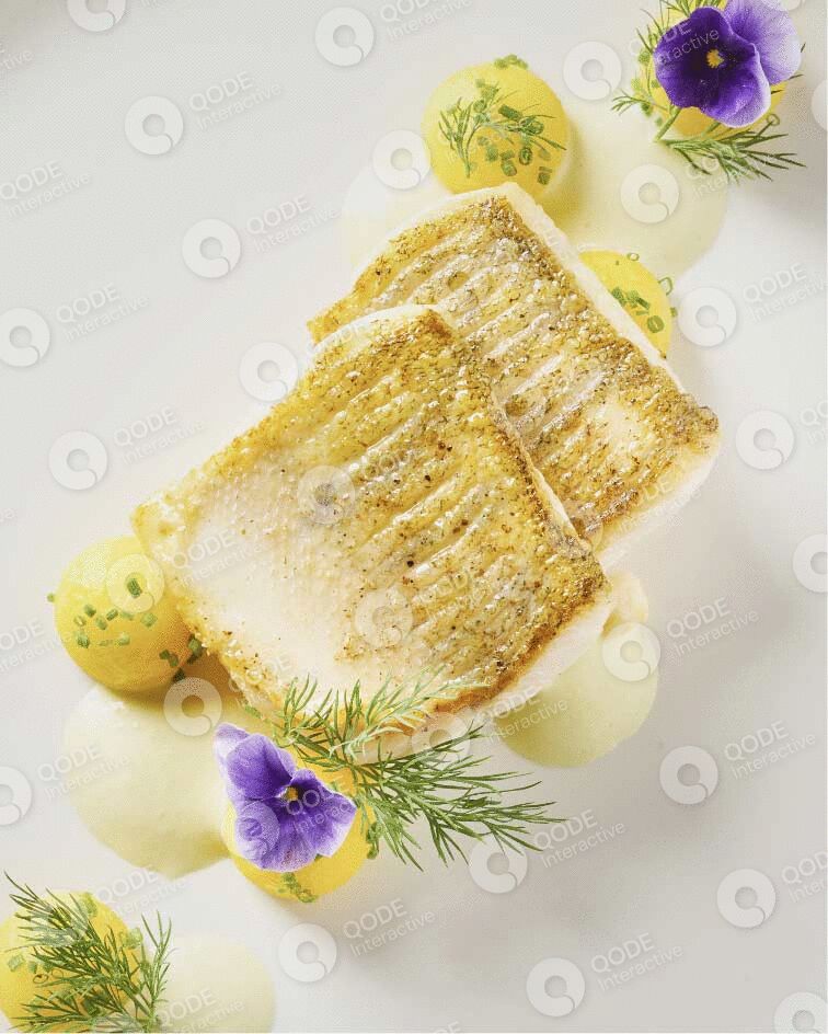 Elegant white cake slice decorated with flowers and herbs.