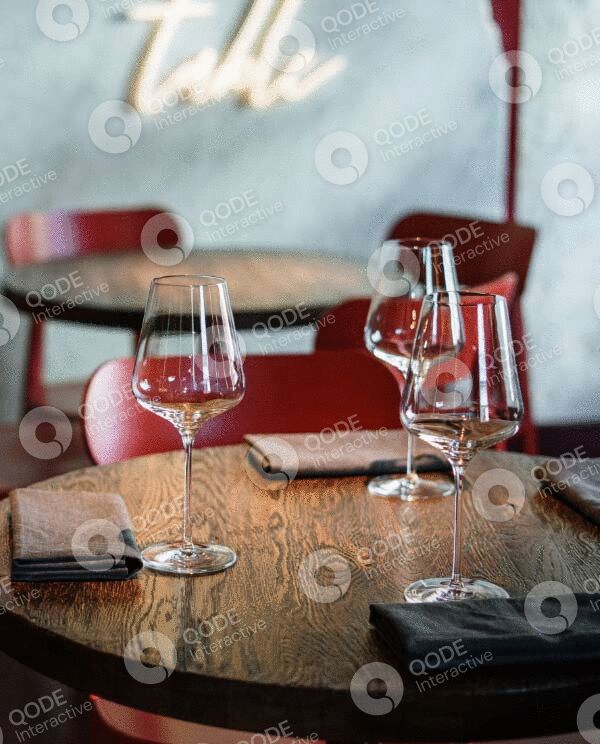 Elegant table setting with wine glasses and napkins on a rustic wooden table.