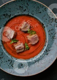 Gourmet dish with sliced meat and sauce on a rustic plate.