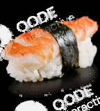 Two pieces of shrimp nigiri sushi with seaweed on black surface.