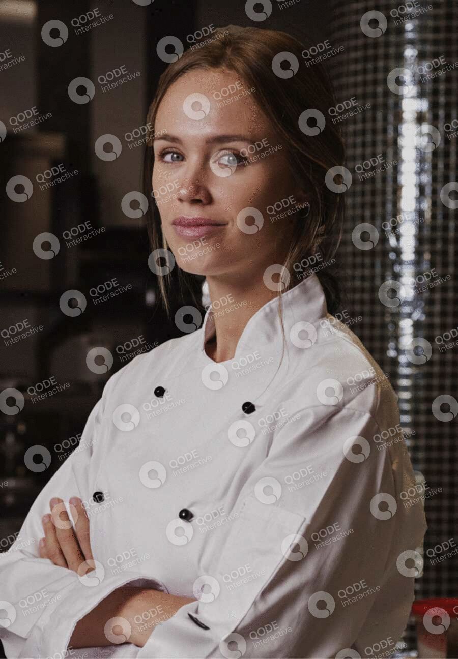 Confident female chef in white uniform with arms crossed.