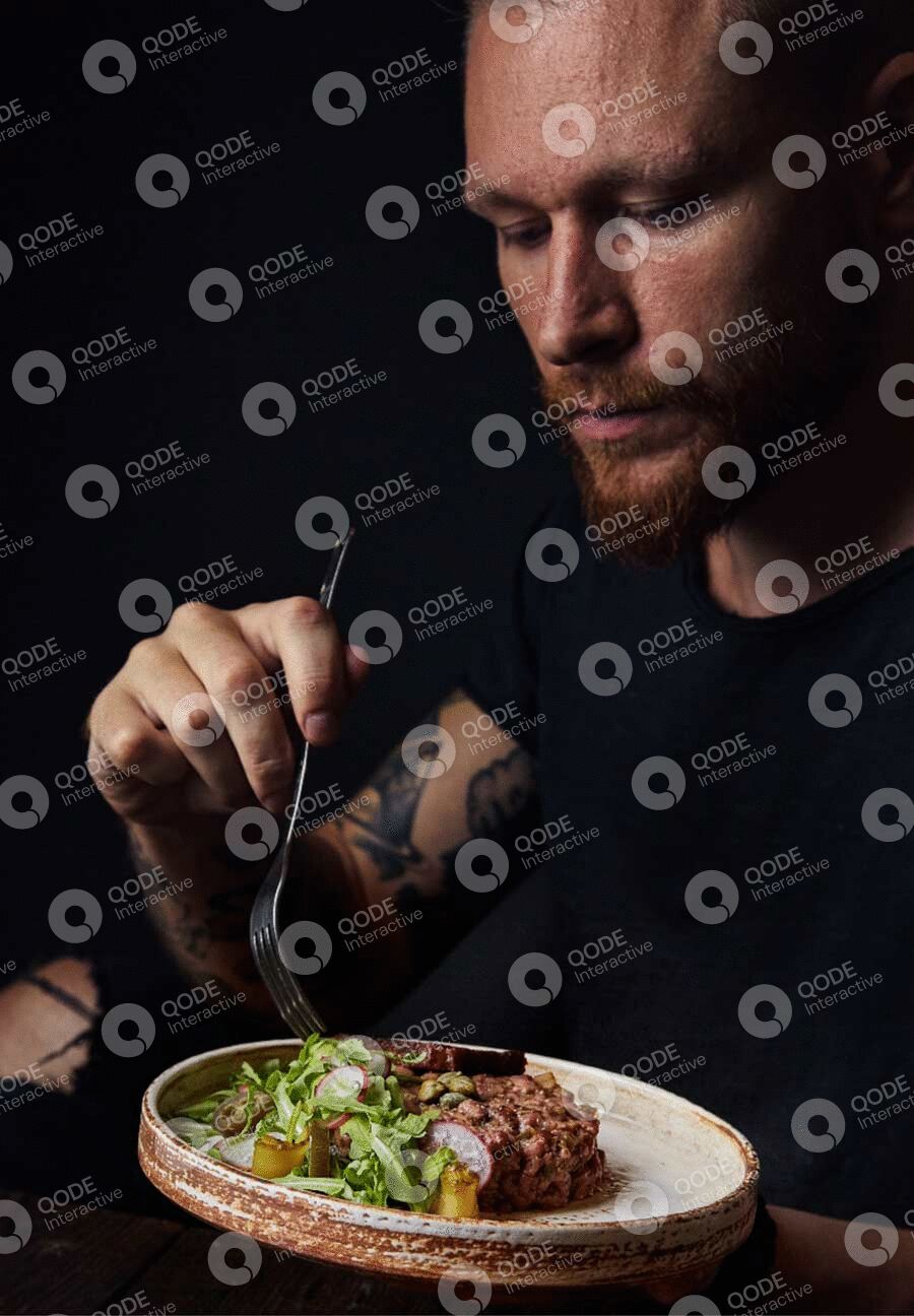 Man sprinkling seasoning on a salad bowl.