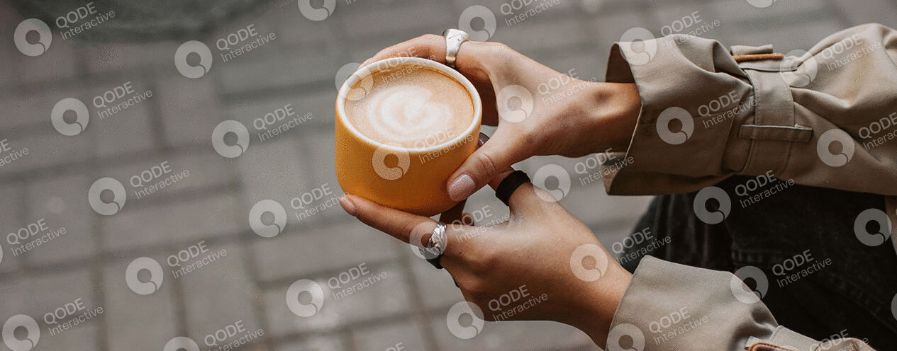 Hands holding a cup of latte with latte art.