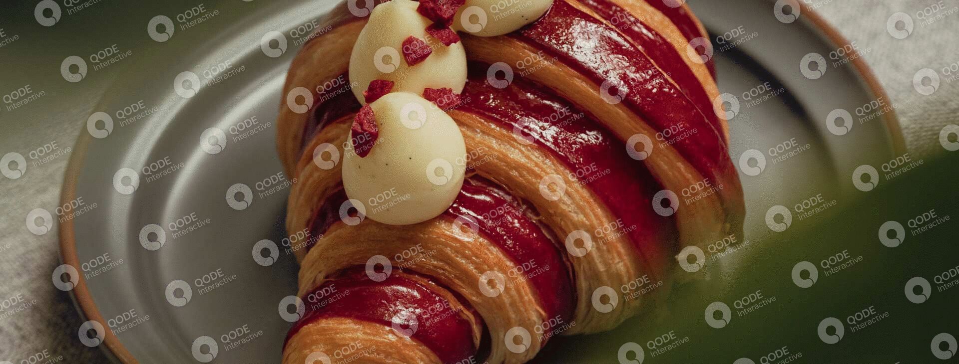 Close-up of a fruit tart with glossy red glaze and dollops of cream.