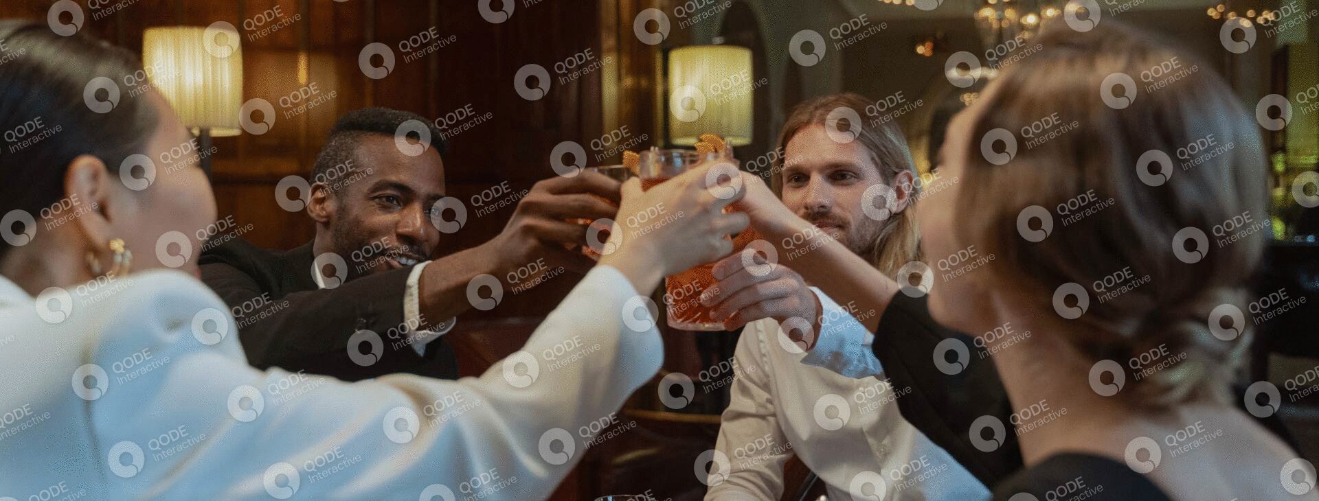 People raising glasses in a toast during a social gathering indoors.