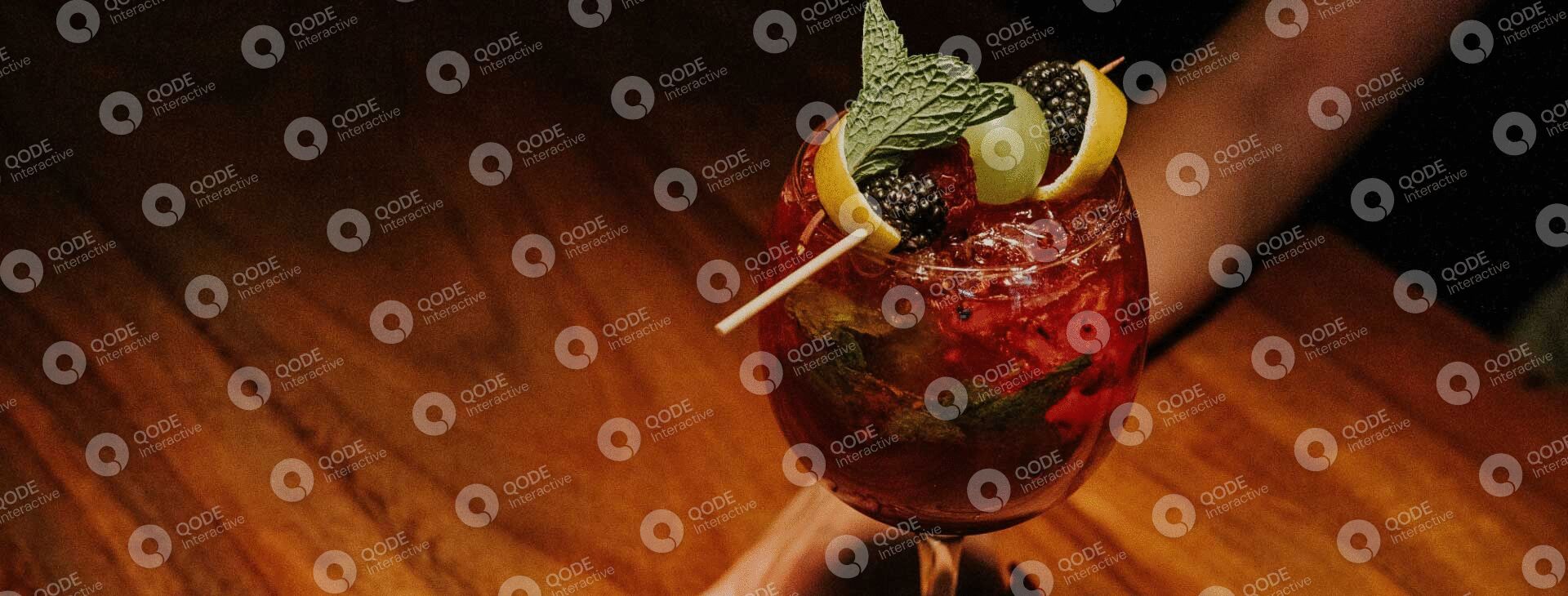 A vibrant cocktail garnished with citrus and herbs on a wooden table.