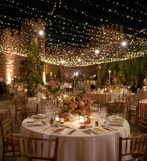Elegant outdoor dining setup under twinkling lights at night.